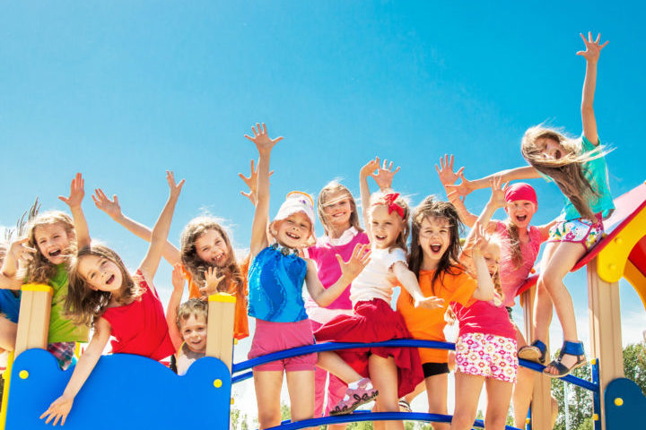 Grupa ubranych na kolorwo dzieci stoi na niebieskim mostku