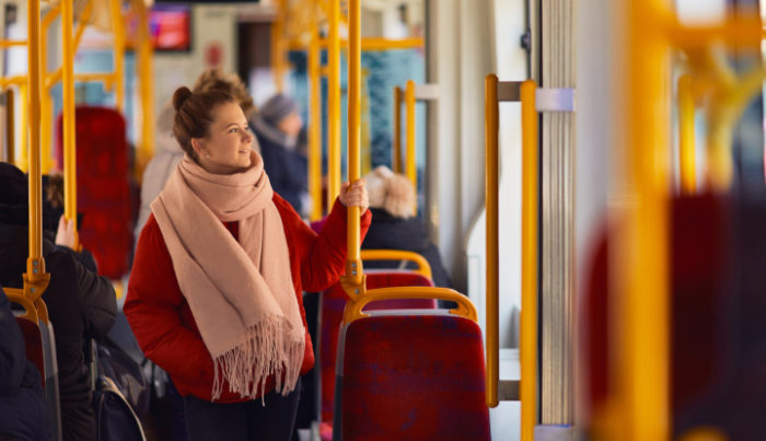 Kobieta w czerownej kurtce i brązowym szalu w środku autobusuKobieta w czerwonej kurtce i brązowym szalu w środku autobusu miejskiegomiejskiego