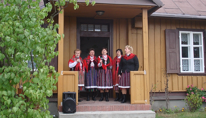 Ganek Izby Regionalnej w Gliniance. Pięć kobiet w strojach ludowych śpiewa piosenkę regionalną