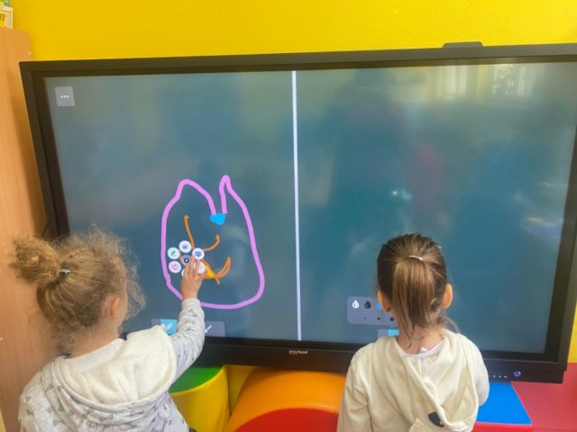 Dwie dziewczynki rysując cos na tablicy interaktywnej