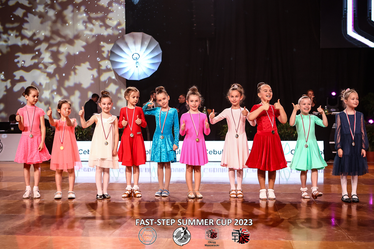 Turniej tańca towarzyskiego. Dziewczynki w kolorowych sukienkach stoją w rzędzie obok siebie.