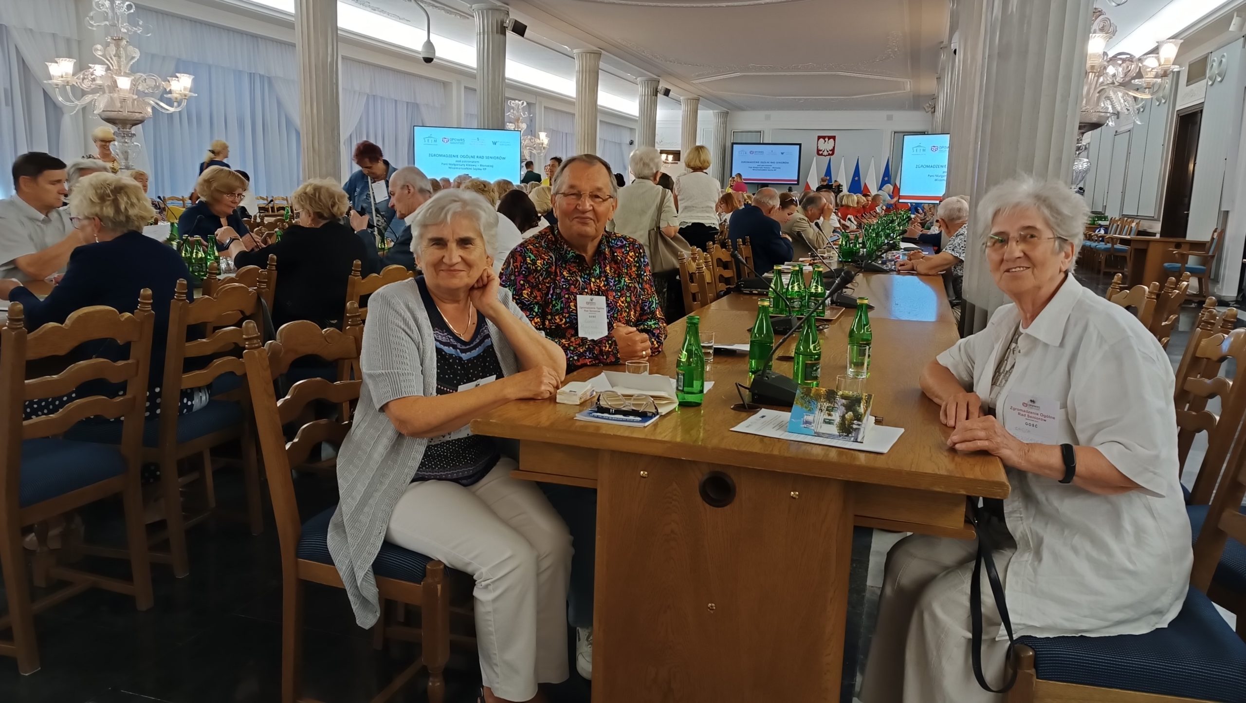 Przedstawiciele Rady Seniorów Gminy Wiązowna siedzą przy stole w sali kolumnowej podczas Zgromadzenia Ogólnego Rad Seniorów w Sejmie RP.