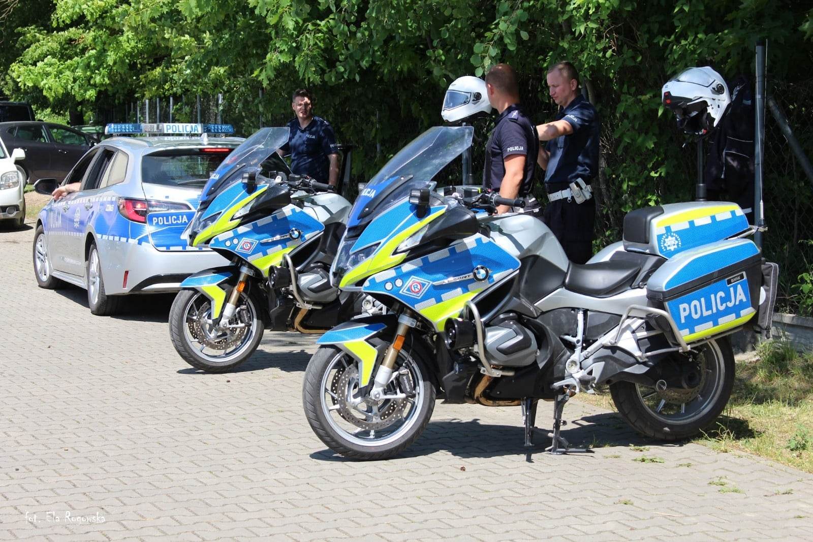 Trzech policjantów, dwa motocykle policyjne i radiowóz.