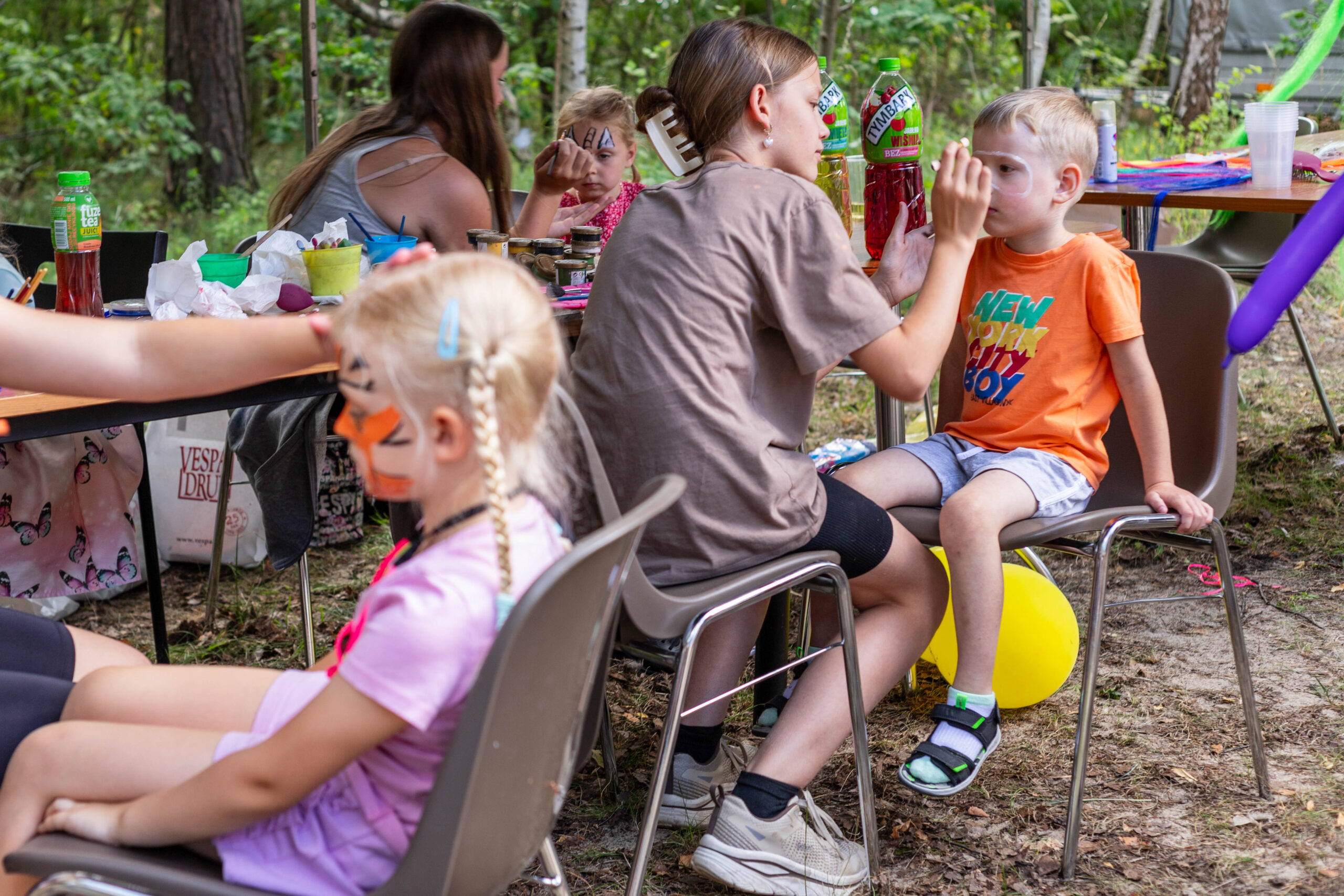 Młode dziewczyny malują dzieciom buzie.